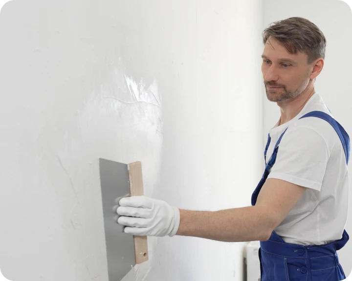 Worker smoothing wall plaster