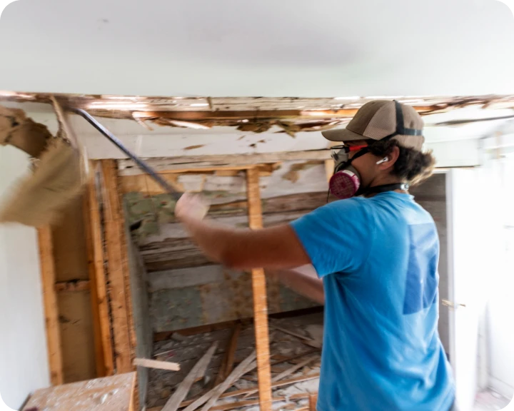 Person demolishing wall with crowbar