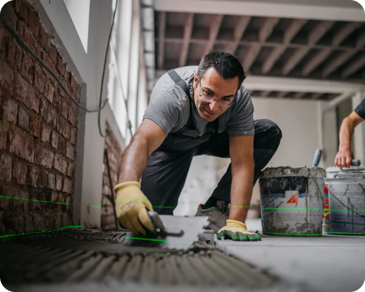 Worker laying tiles in a room